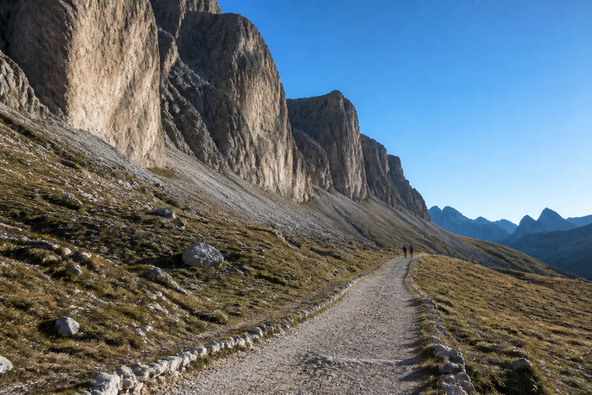 Sentier de terre battue longeant les parois sud des Tre Cime di Lavaredo sous un ciel matinal dégagé