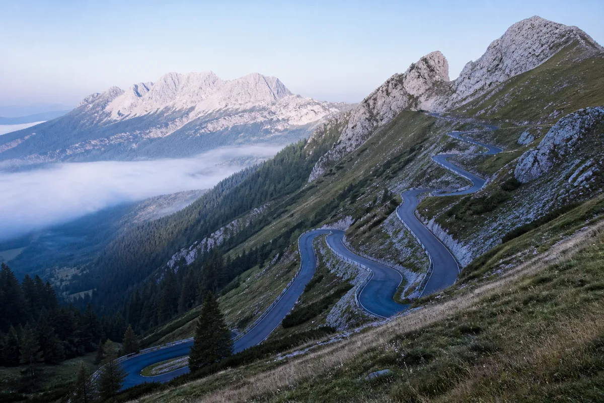 Route de montagne en lacets grimpant vers un col rocheux des Dolomites au petit matin